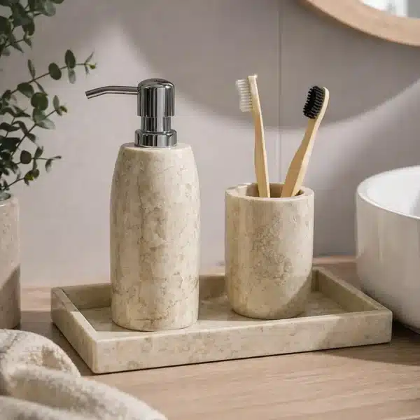 Set de accesorios de baño de mármol beige con dispensador de jabón y vaso sobre bandeja en encimera de baño moderno