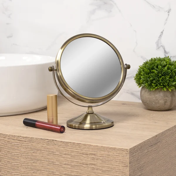 Espejo de aumento 7x con acabado oro viejo sobre encimera de madera en baño con estilo vintage
