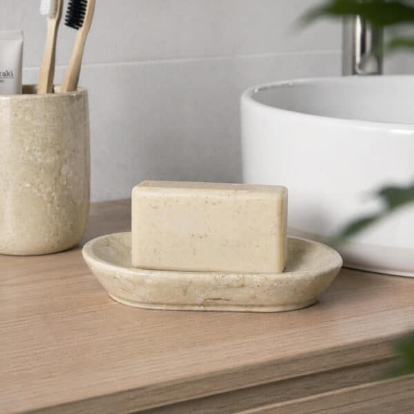 Jabonera de baño de mármol beige con pastilla de jabón sobre encimera en baño moderno